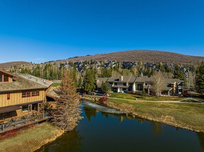 A residential area with houses, a small body of water, and a hill in the background.