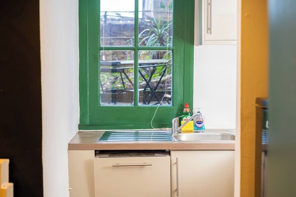 A kitchen with a green window, a sink, and a dishwasher.