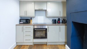 A compact kitchen with a microwave, toaster, kettle, and oven. - 1BR, Whitechapel, Brick Lane, Spitalfields (London)