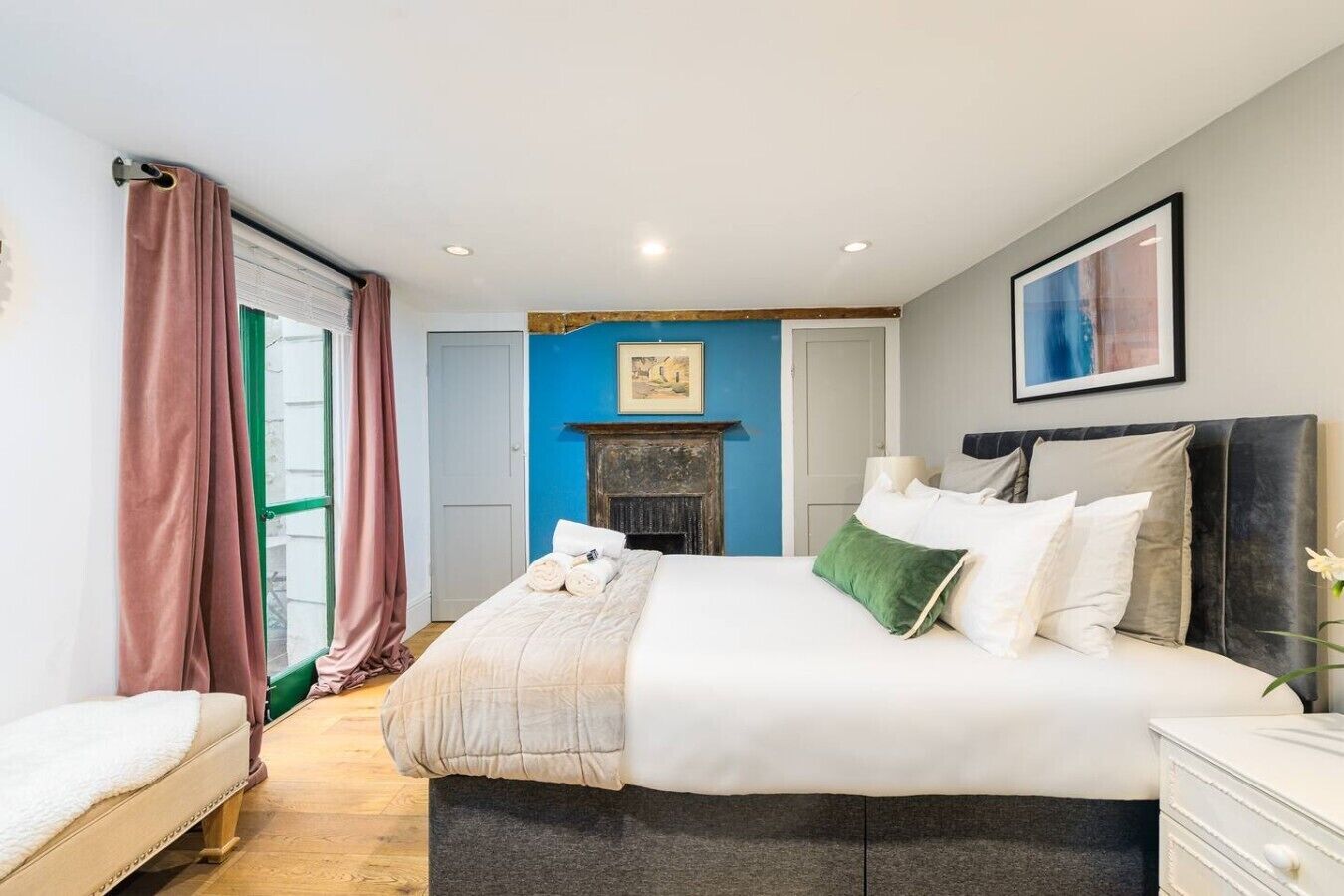 A bedroom with a bed, a dresser, a fireplace, and a door. - 1BR, Whitechapel, Brick Lane, Spitalfields (London)
