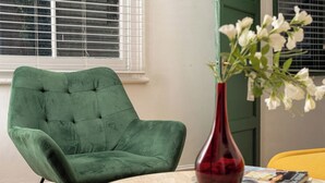 A green armchair, a red vase with white flowers, and a yellow chair. - 1BR, Whitechapel, Brick Lane, Spitalfields (London)