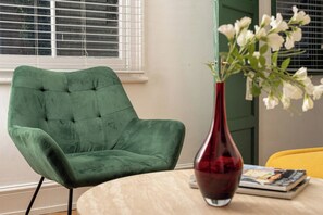 Un fauteuil vert, un vase rouge avec des fleurs blanches et une chaise jaune.