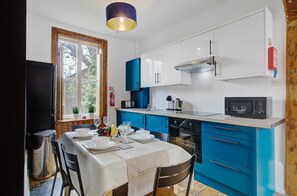 A compact kitchen with white and blue cabinets, a stainless steel sink, a microwave, and a gas stove.