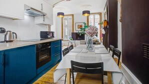A modern kitchen with blue cabinets, a dining table set for four, and a vase with flowers.