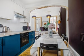 A modern kitchen with blue cabinets, a dining table set for four, and a vase with flowers.