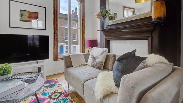 A living room with a TV, sofa, fireplace, and a large window.