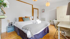 A modern bedroom with a bed, bedside table, lamp, and a wardrobe.