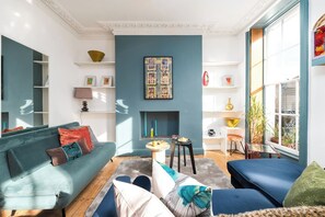 A living room with a teal wall, a fireplace, and a large window with a view. - Stunning luxury flat in Prime Central London (London)