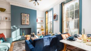A modern living room with a blue sofa, a dining table, and a fireplace. - Stunning luxury flat in Prime Central London (London)