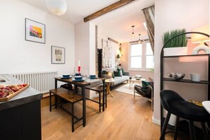 Een moderne woonkamer met een eethoek, een bank, een salontafel en een boekenkast.
