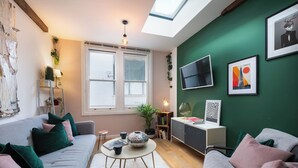 Una sala de estar acogedora con un sofá, una mesa de centro, un televisor y una estantería.