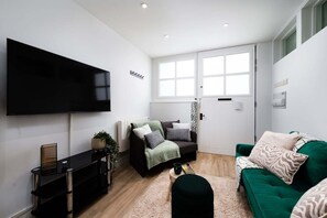 A modern living room with a flat-screen TV, a sofa, a chair, and a coffee table. - Stylish Finsbury Park Flat | Lounge | Fast WiFi (London)