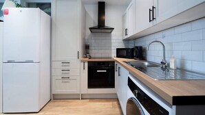 A modern kitchen with white cabinets, a stainless steel sink, a microwave, and a built-in oven. - Stylish Finsbury Park Flat | Lounge | Fast WiFi (London)