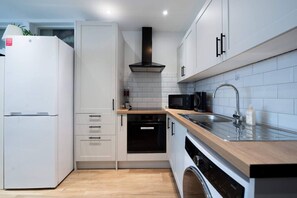 A modern kitchen with white cabinets, a stainless steel sink, a microwave, and a built-in oven.