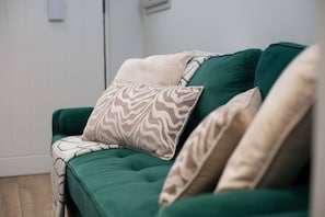 A green sofa with patterned cushions.
