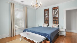 Une chambre à coucher comprenant un lit, une table de chevet, une table, un lustre et des panneaux décoratifs sur les murs.