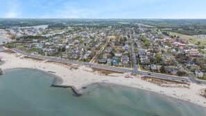 An aerial view of a coastal town with a beach, residential areas, and a water tower. - Salt & Pine | Two Blocks from the Beach (Cape Charles)