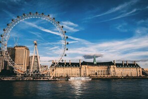 A Ferris wheel, a historic building, and a river.