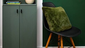 A green cabinet with two wooden vases, a bowl, and books. A green chair with a cushion is next to it. - Central London | King Bed | Smart Tv | Big Windows (London)