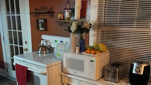 A compact kitchen with a stove, microwave, toaster, and a clock on the wall. - 3-bedroom duplex yellow house downtown  Des Moines with AC, WiFi (des moines)