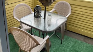 A balcony with a table and chairs, a hanging umbrella, and a view of a street with cars and trees. - 3-bedroom duplex yellow house downtown  Des Moines with AC, WiFi (des moines)