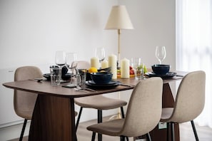 A dining table set with plates, glasses, candles, and a lamp.