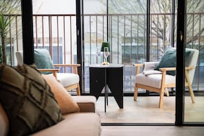 A balcony with two chairs, a small table, and a glass of wine.