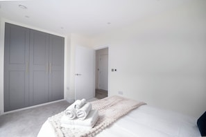 A bedroom with a bed, a grey wardrobe, and a white door.