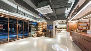 A modern interior with a reception desk, glass doors, and a lounge area with seating and decor. - James Joyce Coffetel (Beijing South Railway Station Yongdingmenwai Subway Station) (Beijing)