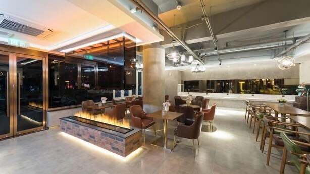 A modern indoor space with a central fire feature, seating areas, and a bar counter. - James Joyce Coffetel (Beijing South Railway Station Yongdingmenwai Subway Station) (Beijing)