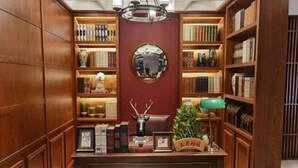 A library with wooden bookshelves, a central desk with decorative items, and a mirror on the wall. - James Joyce Coffetel (Beijing South Railway Station Yongdingmenwai Subway Station) (Beijing)