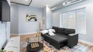 A modern living room with a grey sofa, a glass coffee table, and a patterned rug. - Charming 2-bedroom apartment in fabulous Westchester with AC, WiFi (Westchester)