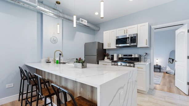 A modern kitchen with white cabinets, stainless steel appliances, and a central island with bar stools. - Charming 2-bedroom apartment in fabulous Westchester with AC, WiFi (Westchester)