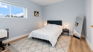A bedroom with a bed, bedside tables, a desk, a mirror, and a window. - Charming 2-bedroom apartment in fabulous Westchester with AC, WiFi (Westchester)
