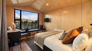 Une chambre avec une grande fenêtre, un lit, un bureau et une chaise.
