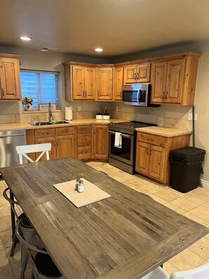 A kitchen with wooden cabinets, a stainless steel sink, a microwave, and a dining table.