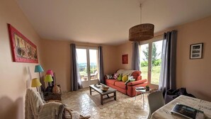 Een woonkamer met een bank, een salontafel, een lamp en uitzicht door een groot raam.