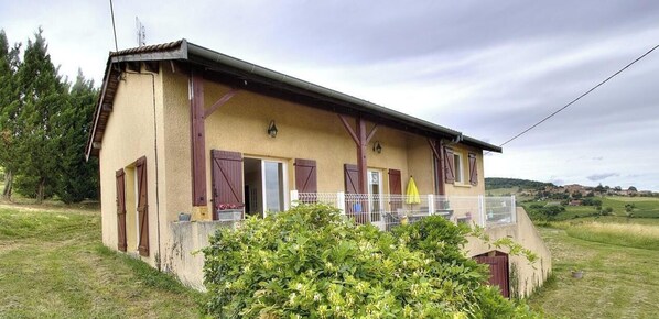 A two-story building with a balcony, a small attached shed, and a grassy area with trees. - La Treille - FRONTENAS (FRONTENAS)