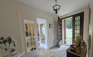 A hallway with a white door, a potted plant, and a wooden table with decorative items. - La Treille - FRONTENAS (FRONTENAS)