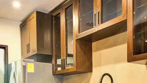 A kitchen with dark wooden cabinets, a stainless steel refrigerator, and a black faucet.