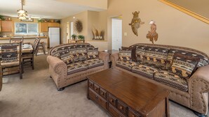 A living room with a sectional sofa, wooden coffee table, and a dining area with a wooden table and chairs.
