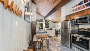 Una cocina moderna con vigas de madera, electrodomésticos de acero inoxidable y un comedor con mesa y banco de madera.