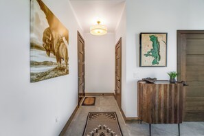 A hallway with a wooden door, a wall-mounted light fixture, and a framed map. - Located in Downtown Whitefish,Walk to Dining and Shops- Nearby Lake and Ski! (Whitefish)