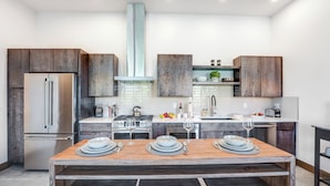 A modern kitchen with a central island, stainless steel appliances, and wooden cabinetry. - Located in Downtown Whitefish,Walk to Dining and Shops- Nearby Lake and Ski! (Whitefish)