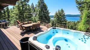 Un bain à remous sur une terrasse en bois, avec vue sur un lac et des arbres.