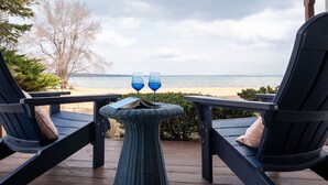 A deck with two lounge chairs facing a beach.