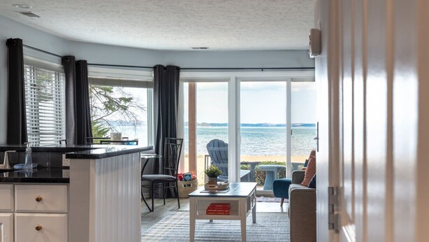 A modern kitchen with a view of the sea, a dining area with a table and chairs, and a cozy seating area with a view.