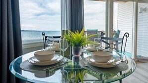 Mesa de vidrio dispuesta para comer con vista al mar.