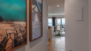 Un pasillo con piso de madera que conduce a un balcón con vista al mar.