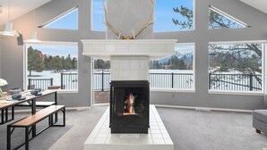 Una sala de estar moderna con chimenea, ventanas amplias y vista a un paisaje nevado.